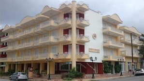 Un hôtel à plusieurs étages, doté de balcons, d’une colonne centrale et d’une enseigne indiquant qu’il s’agit d’un hôtel.