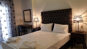Un lit bien fait, avec du linge de lit blanc, une tête de lit capitonnée et deux lampes de chevet.