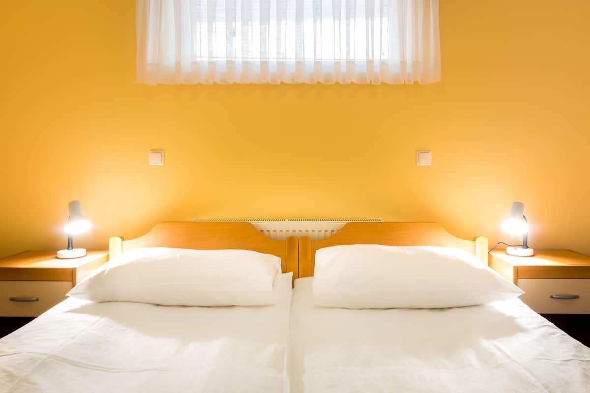 A double bed with white bedding, two bedside lamps, and a wooden headboard.