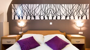 A neatly made bed with two purple pillows, a wall-mounted artwork of bare trees, and bedside lamps on either side. - Rooms & Apartments Kepic (Cerklje na Gorenjskem)