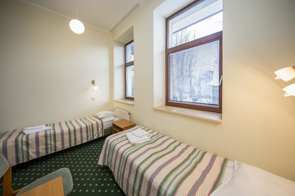 A small, clean room with two single beds, a desk, and a chair.