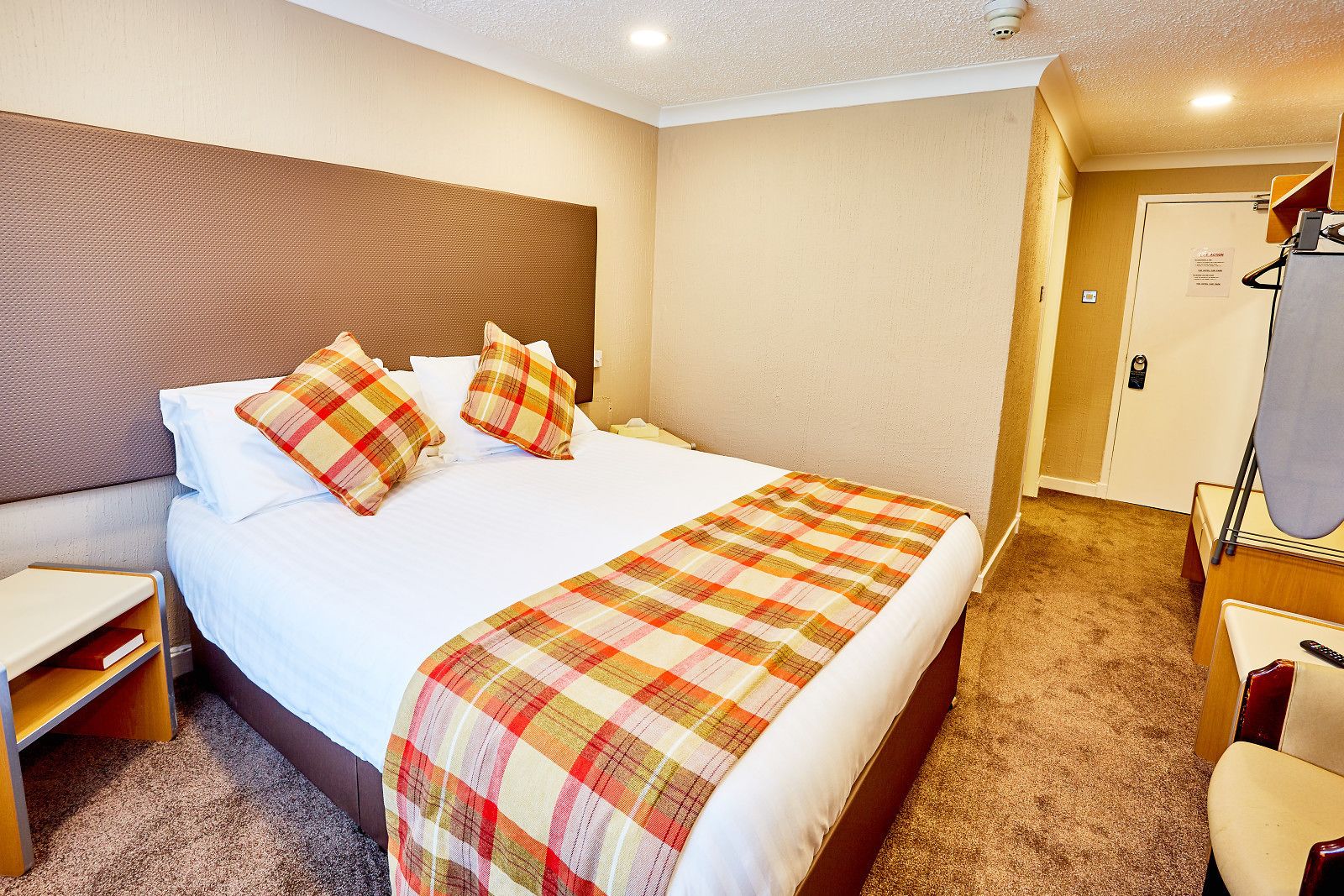 Una habitación de hotel con una cama grande, una mesita de noche, una silla y un espejo.