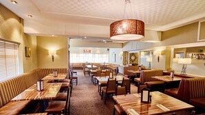 A restaurant with booths and tables, patterned walls, and a hanging light fixture. - Abbotsford Hotel (Dumbarton)