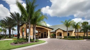 A hotel with a central courtyard, palm trees, and a clear sky.