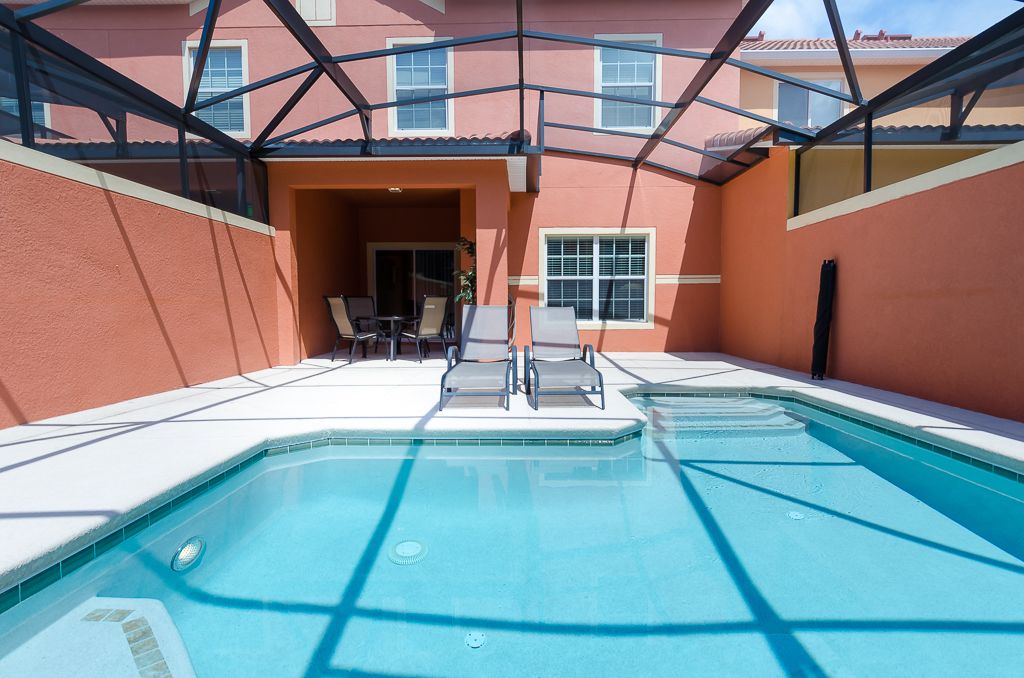 A swimming pool with lounge chairs and a covered patio area.