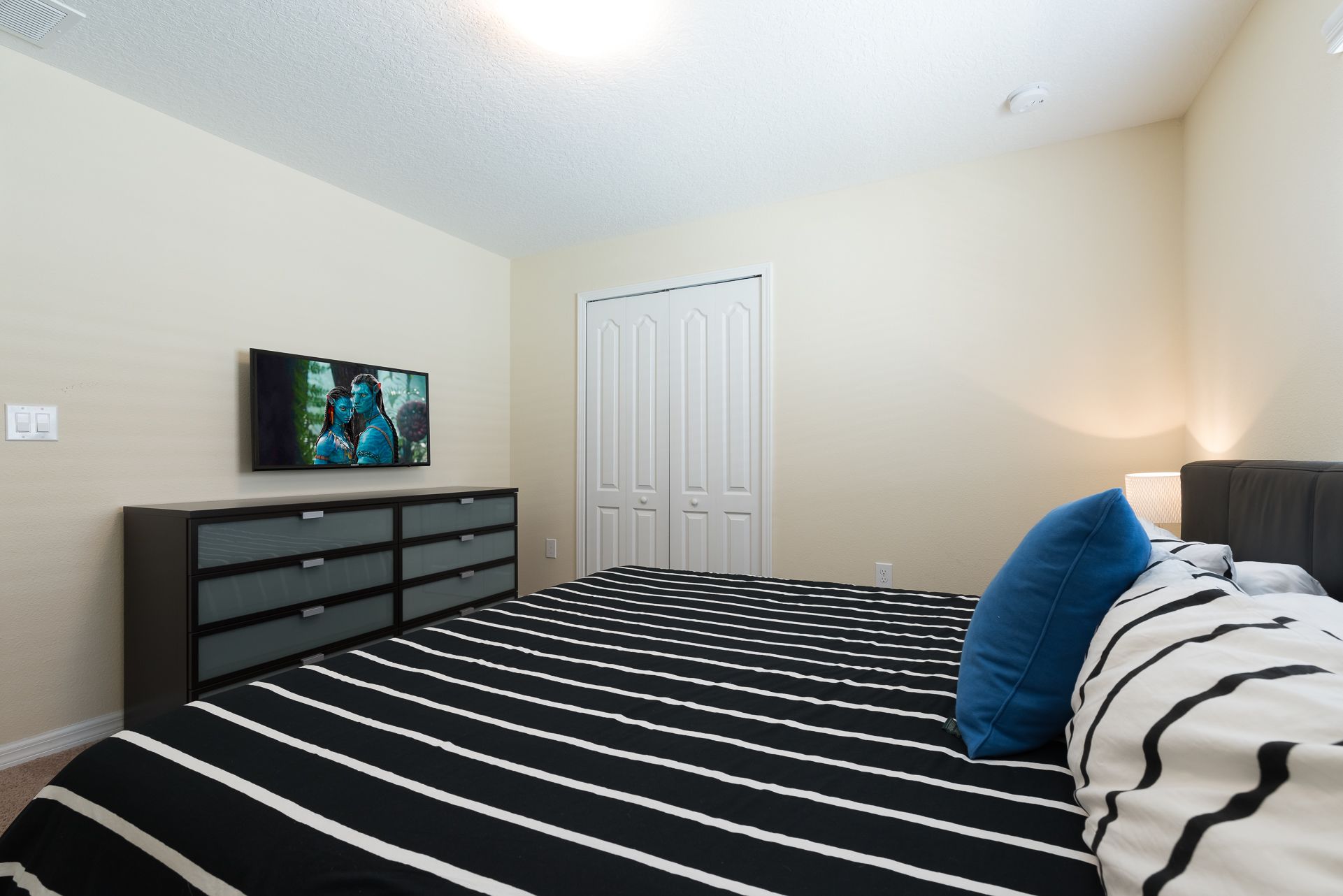 Ein Schlafzimmer mit einem Bett, einem Fernseher, einem Kleiderschrank und einer Tür.