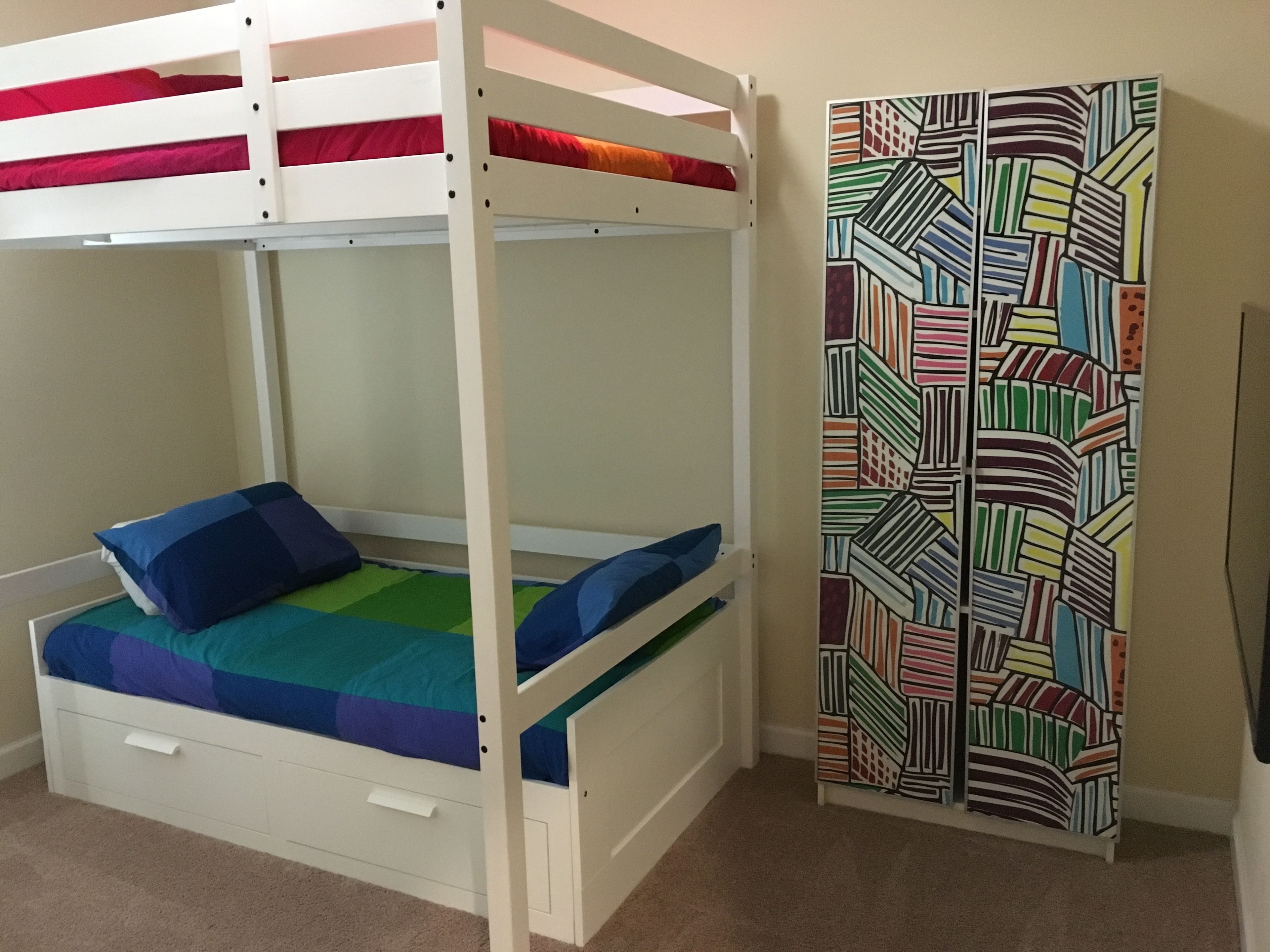 Ein Stockbett mit einer Wand in farbigem geometrischem Muster.