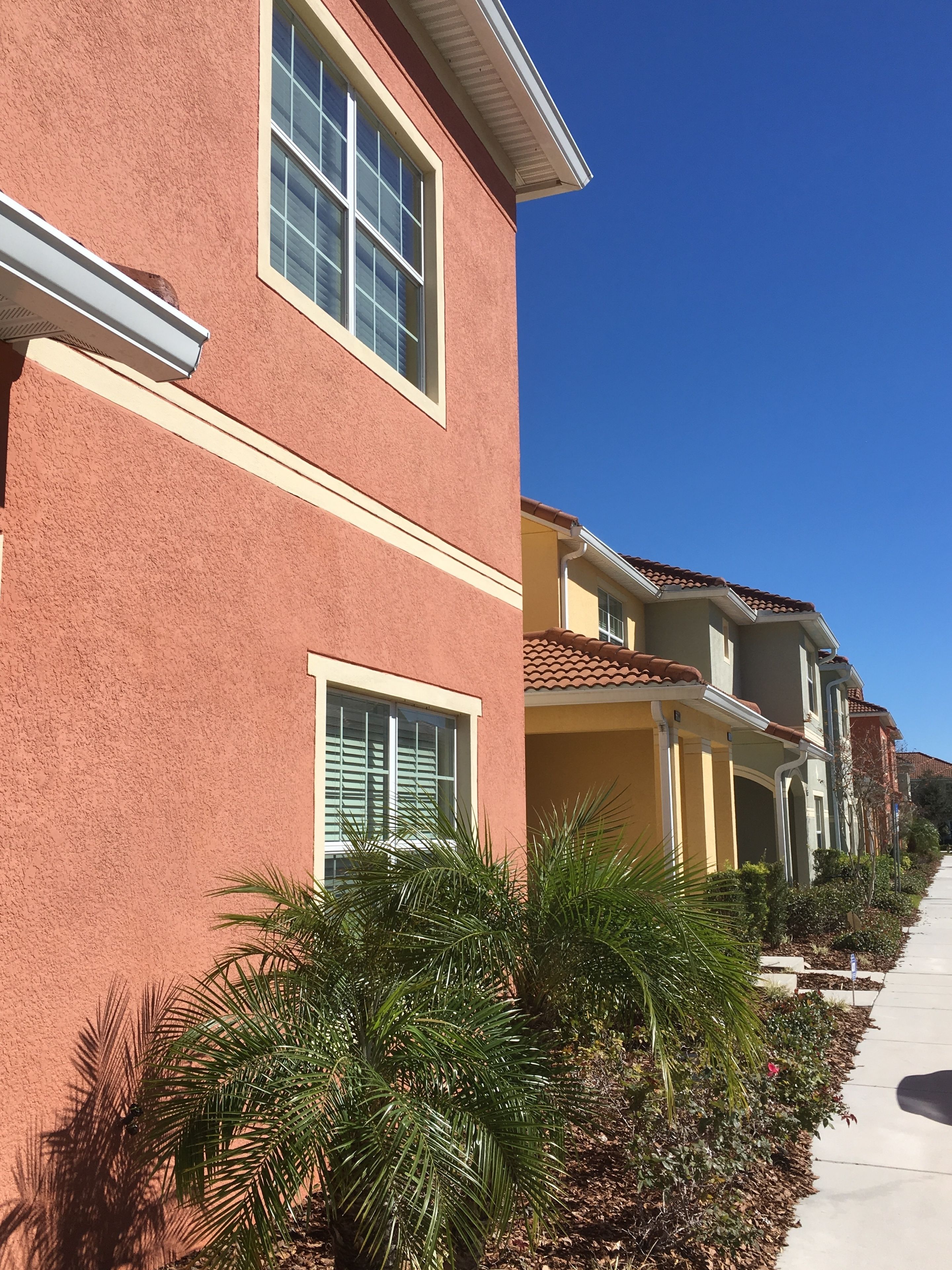 A row of townhouses with a uniform architectural style, featuring large windows and a consistent facade color.