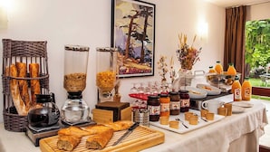 A breakfast buffet with bread, pastries, beverages, and condiments. - Appart Hôtel Corte HR (Corte)