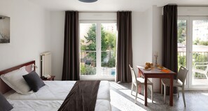 A hotel room with a bed, a table with breakfast, a chair, and a view of the outside. - Appart Hôtel Corte HR (Corte)