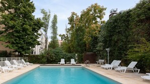 A swimming pool with white lounge chairs and a wooden deck. - Appart Hôtel Corte HR (Corte)