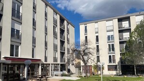 A modern apartment building with multiple balconies, a covered outdoor seating area, and a well-maintained lawn. - Appart Hôtel Corte HR (Corte)