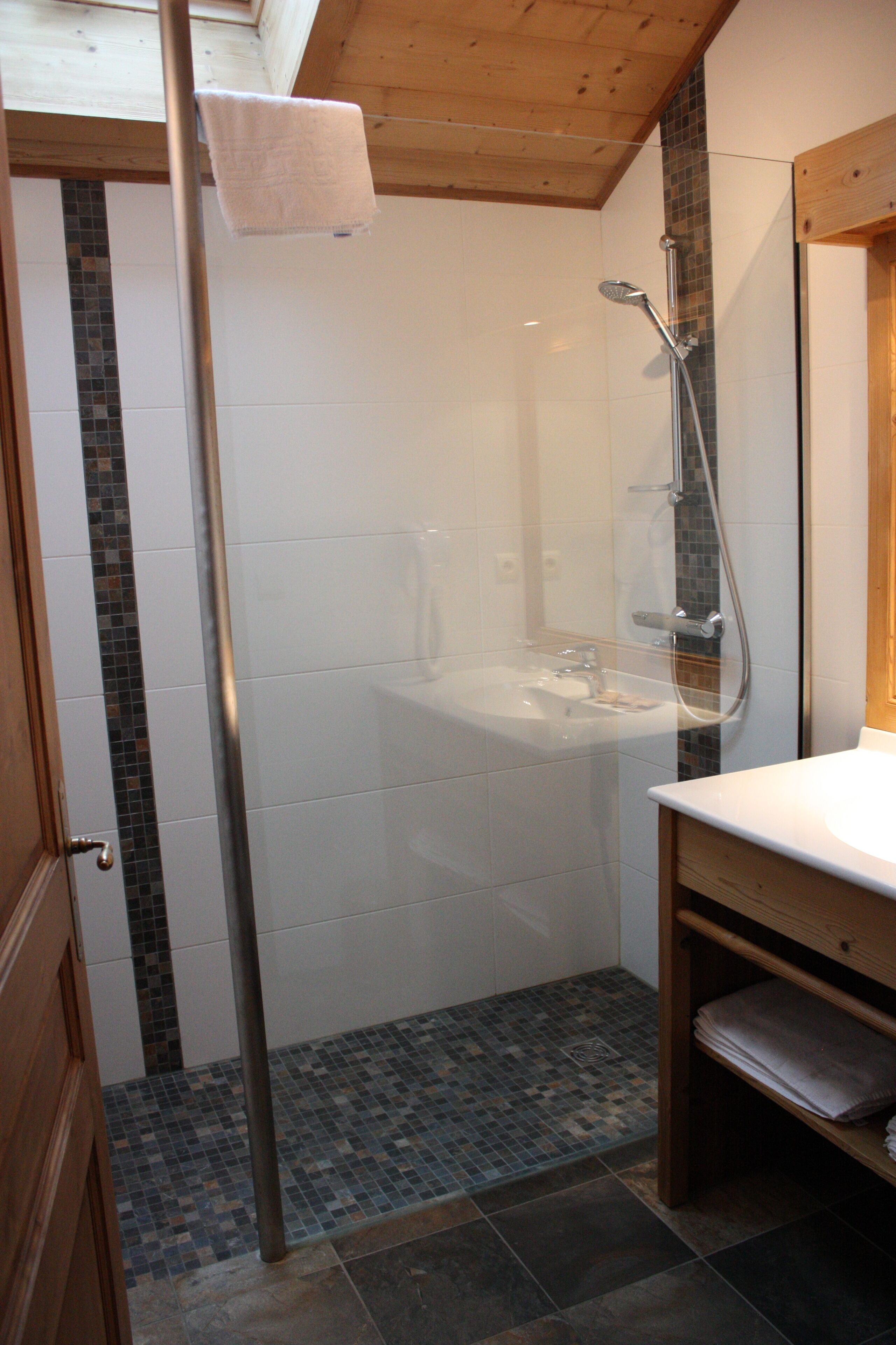 Une salle de bain avec une douche à parois de verre, un lavabo et un meuble-lavabo en bois.