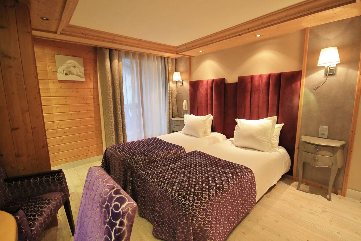 Ein Hotelzimmer mit einem großen Bett, Holzwänden, einer Bank und zwei Nachttischen mit Lampen.