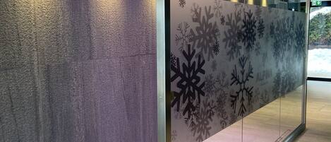 A modern interior with a textured wall, a glass partition with snowflake designs, and a wooden floor.