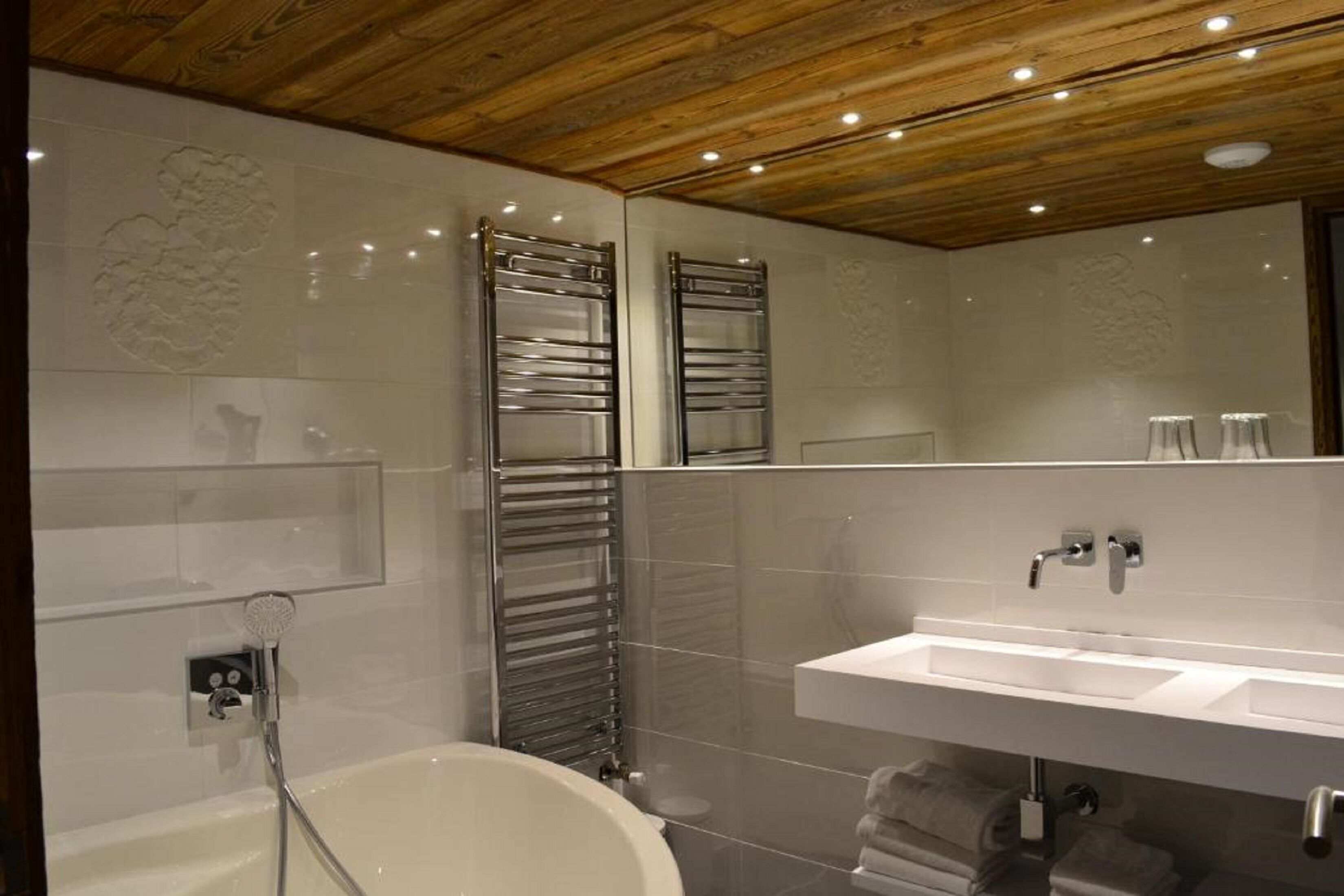 A modern bathroom with a freestanding bathtub, a large mirror, and a built-in sink.