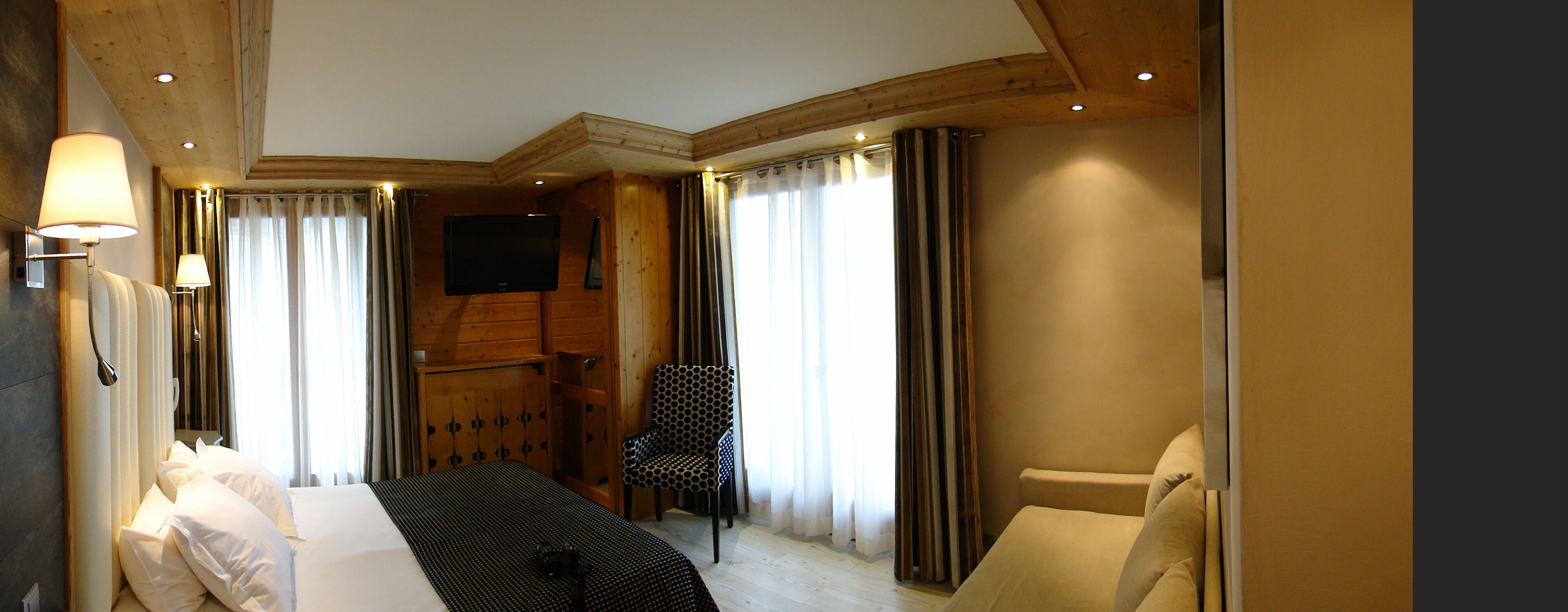 Una habitación de hotel con una cama, una silla, un televisor y cortinas.