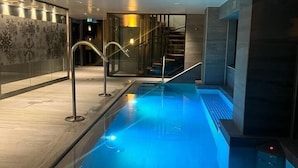 Une piscine intérieure moderne, dotée d’une eau cristalline et entourée d’un décor épuré et minimaliste.