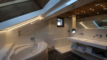 A modern bathroom with a large bathtub, a double sink vanity, and a skylight.