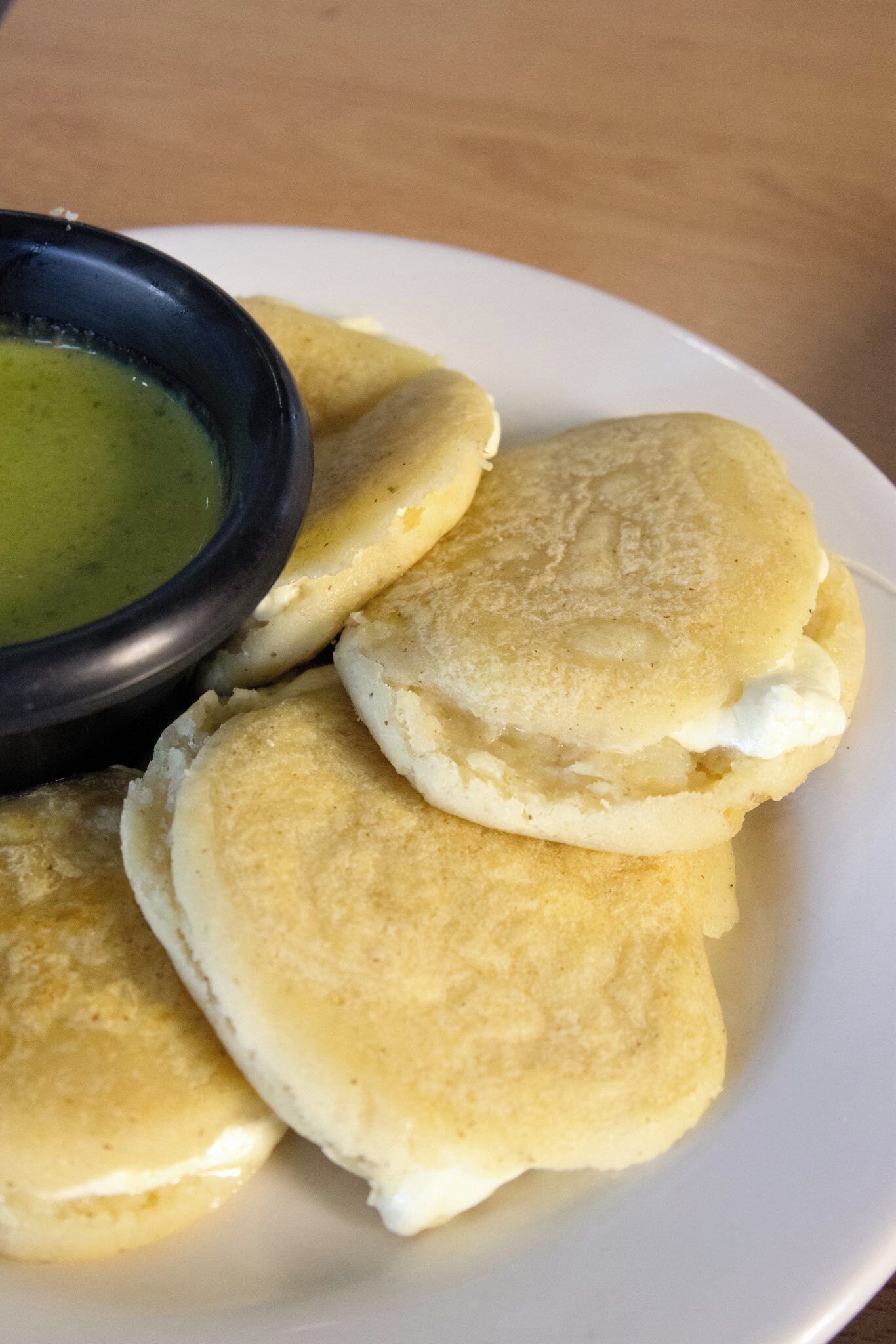 Un plato de arepas con salsa verde acompañada.