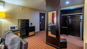 A hotel room with a sofa, a microwave, a small table, a wardrobe, and a mirror. - Paris FC HOTEL (Poza Rica)