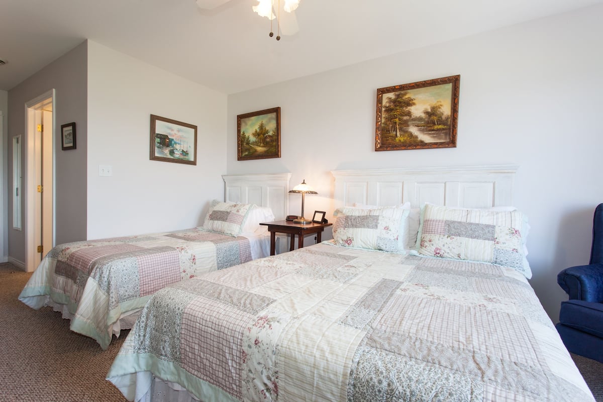 A bedroom with two single beds, a nightstand, a lamp, and a chair.