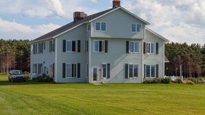 A two-story house with a front lawn, a car parked in the driveway, and a chimney on the roof. - Johnson Shore Inn (Rock Barra)