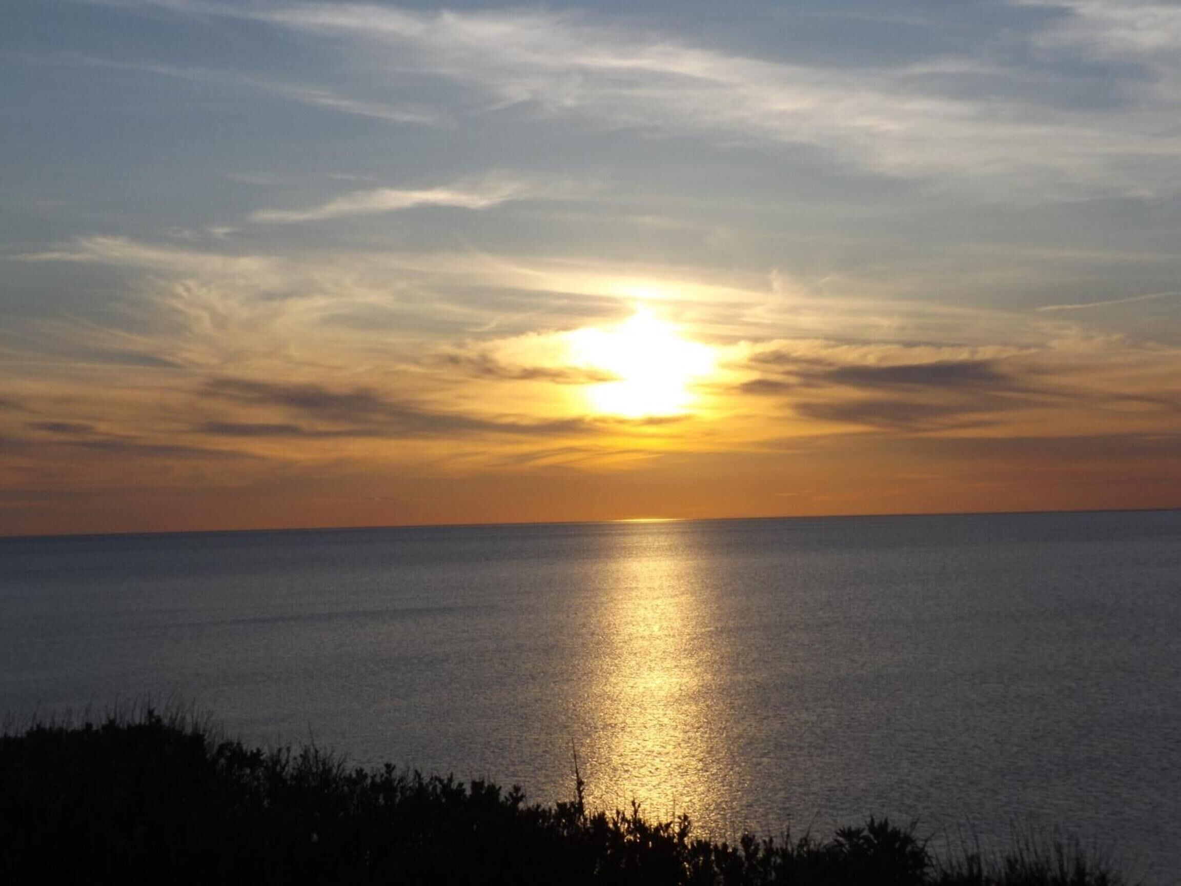 Un atardecer sobre un mar tranquilo con un horizonte despejado.