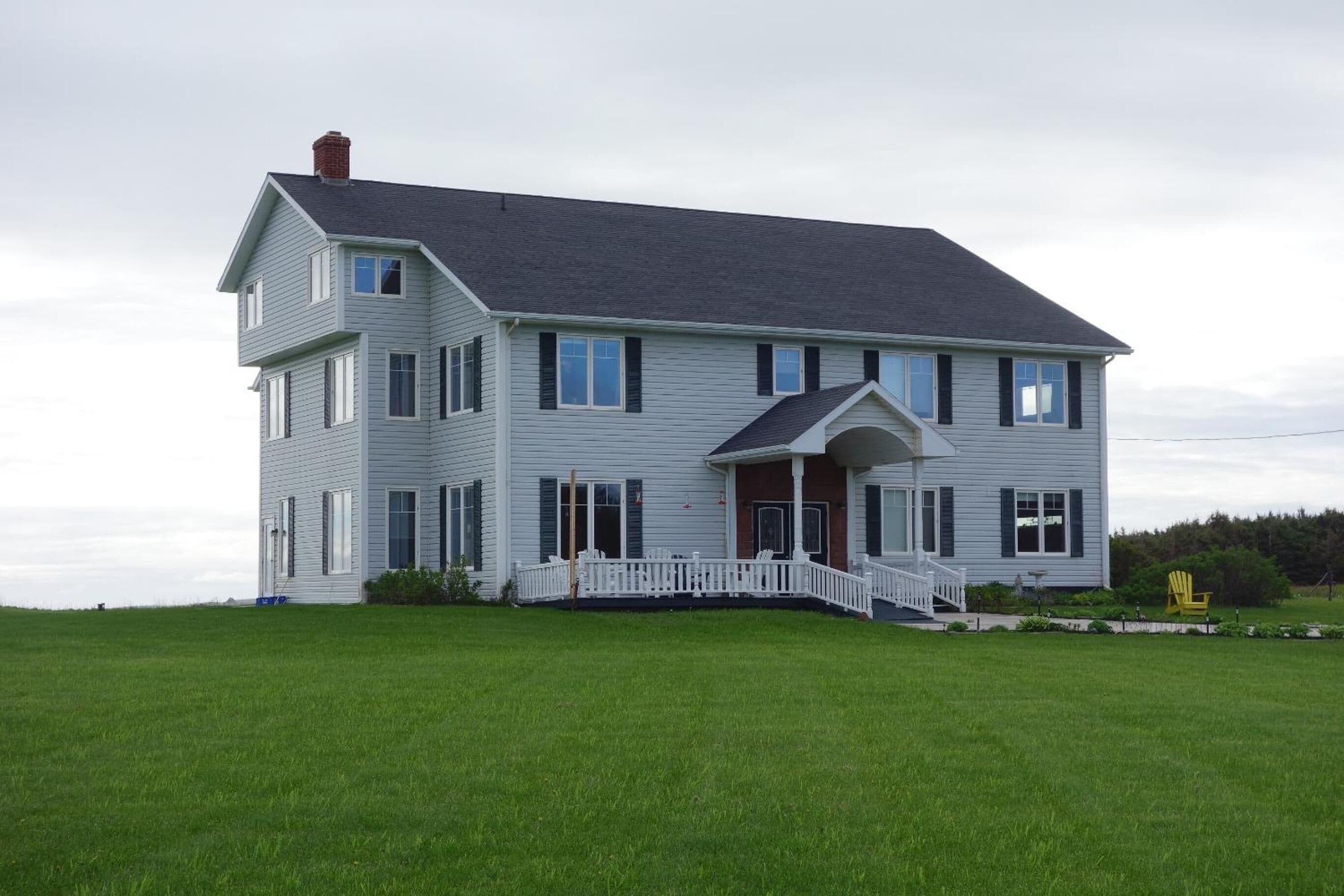 A two-story house with a front porch and a small staircase leading to the entrance.