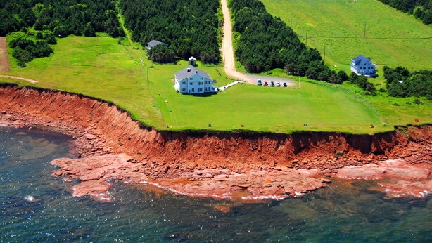 A coastal property with a large house, a dirt path, and a grassy area.