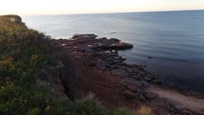 A coastal landscape with rocky terrain and a clear view of the sea.
