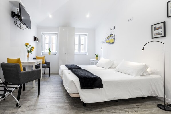 A modern bedroom with a large bed, a desk, and a chair. - Castle Inn Lisbon Apartments (Lisbon)