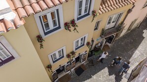Un edificio con tejado de tejas, numerosas ventanas y macetas colgantes de flores.