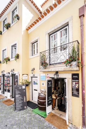 A yellow building with a balcony, a sign for 'Carla Inn', and a menu board outside. - Castle Inn Lisbon Apartments (Lisbon)