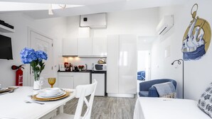 Un espacio habitable moderno y compacto con comedor, kitchenette y dormitorio.