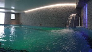 Una piscina interior con agua cristalina, una cascada y una pared de piedra.
