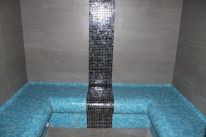 A bathroom with a tiled floor and walls, a central vertical tile feature, and a blue-tiled lower section. - Les Chalets D'Adelphine II (Les Gets)