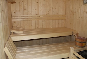 Una sauna con bancos de madera y un balde de madera.