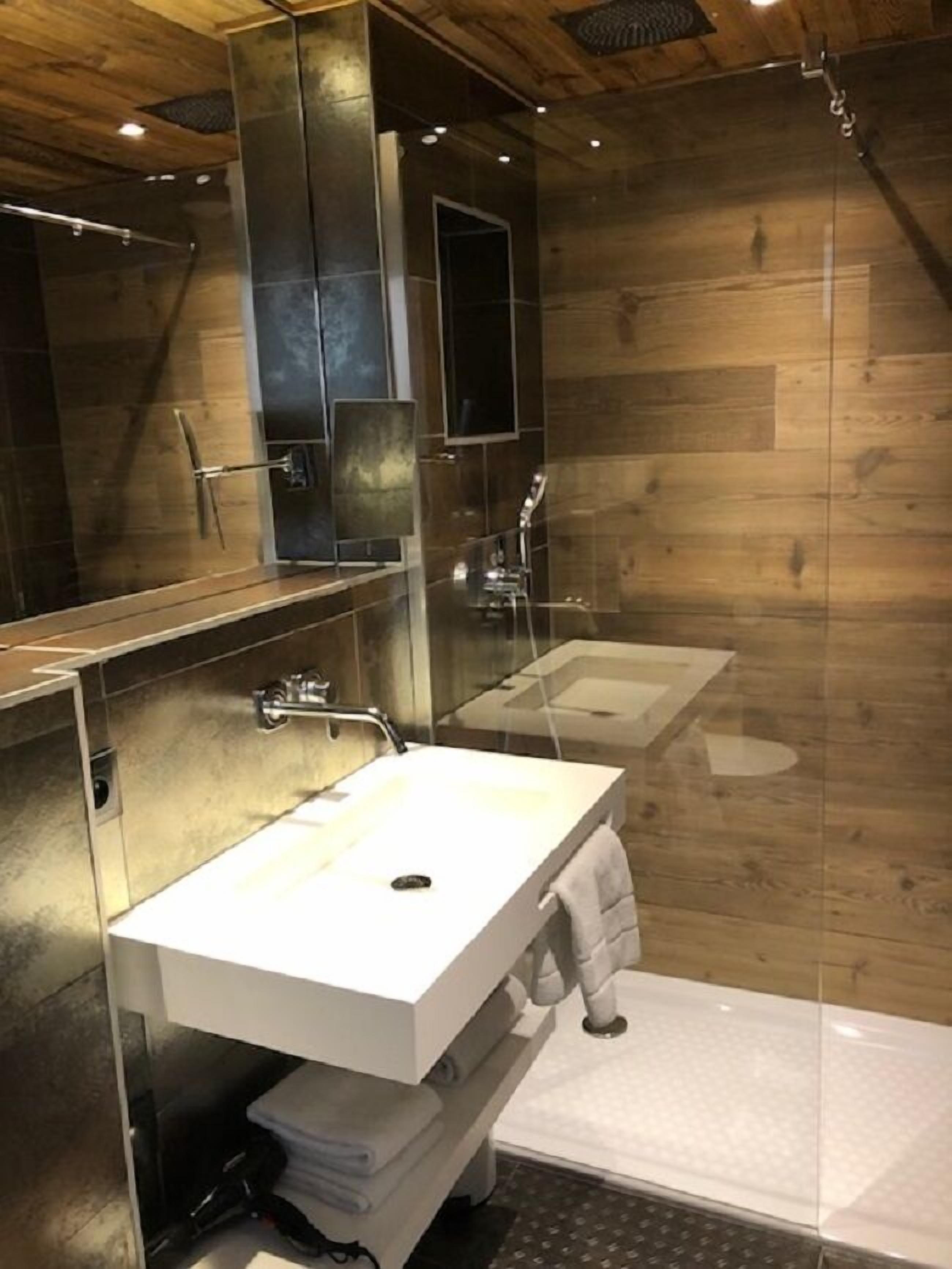 Une salle de bain moderne avec un grand miroir, deux lavabos et une douche.