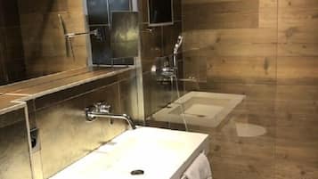 Une salle de bain moderne avec un grand miroir, deux lavabos et une douche.