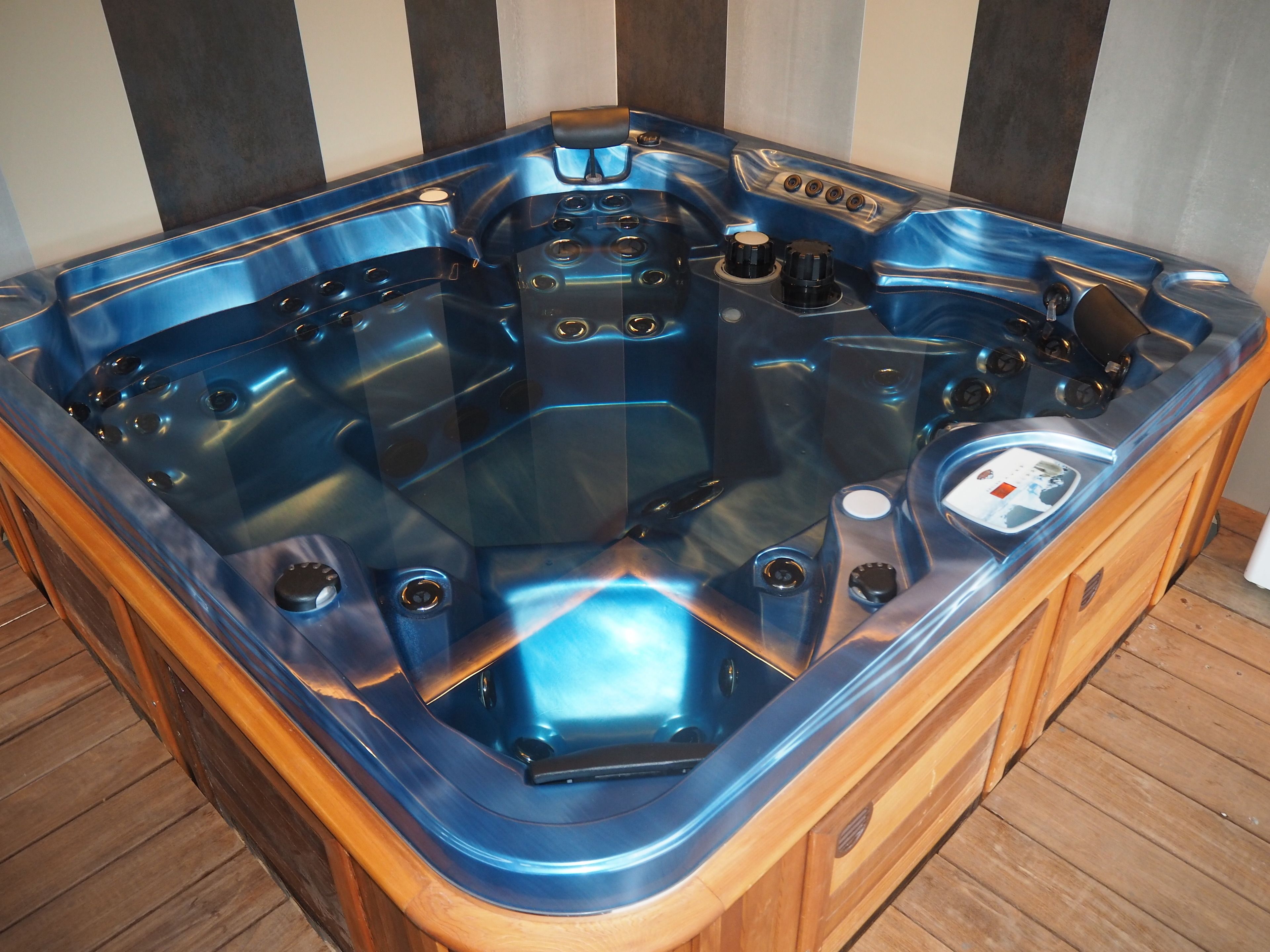A wooden hot tub with a control panel and a built-in seat.