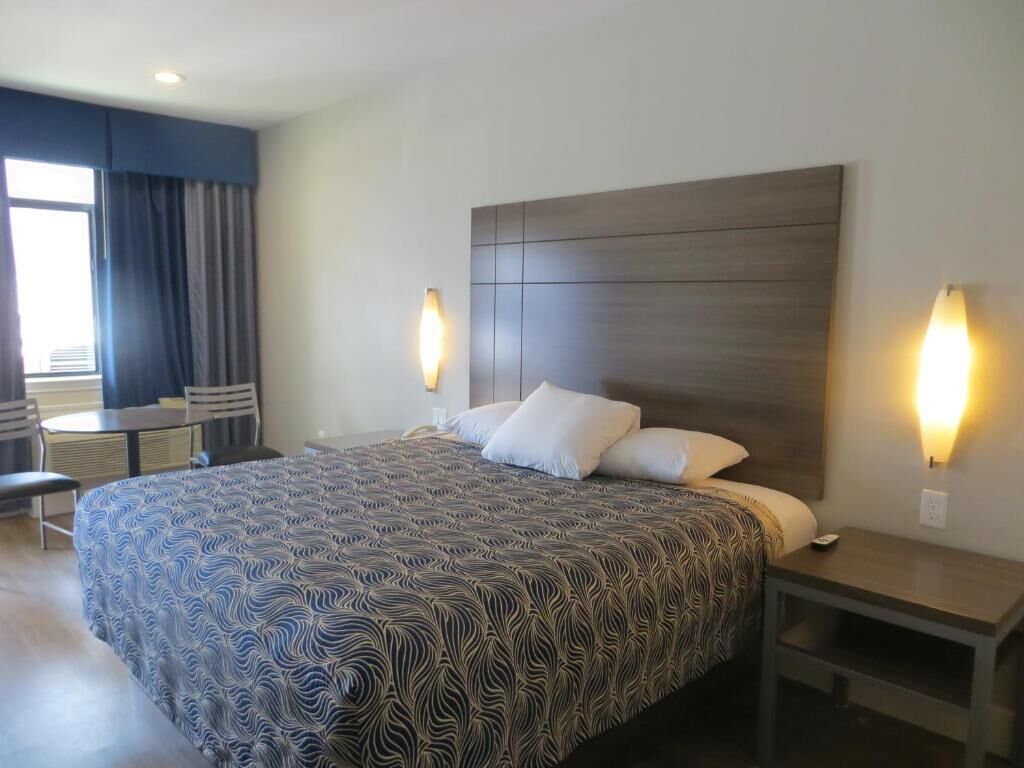 A hotel room with a large bed, two bedside tables, a desk, and a chair.