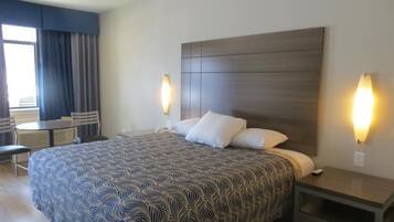 A hotel room with a large bed, two bedside tables, a desk, and a chair.