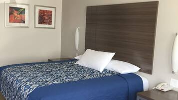A hotel room with a large bed, a bedside table, a nightstand, and two framed pictures on the wall.