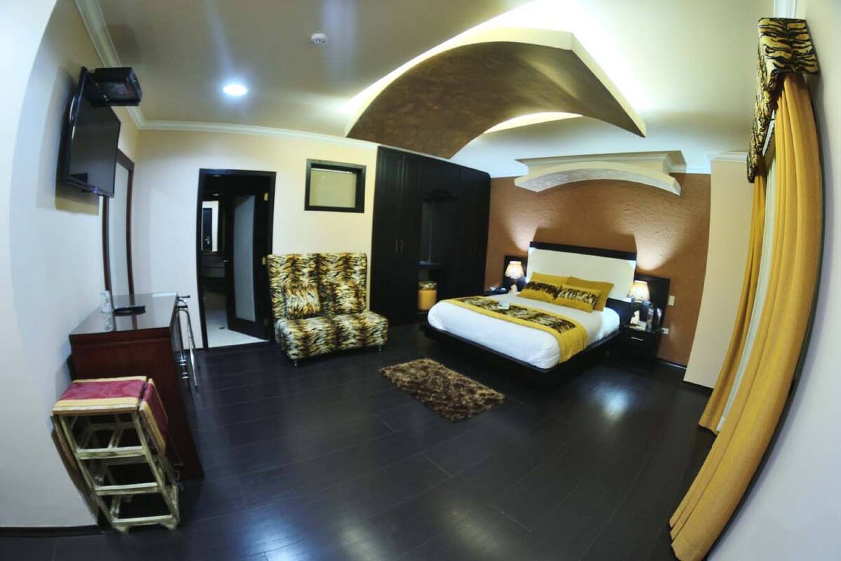 A bedroom with a large bed, a desk, a chair, and a television.