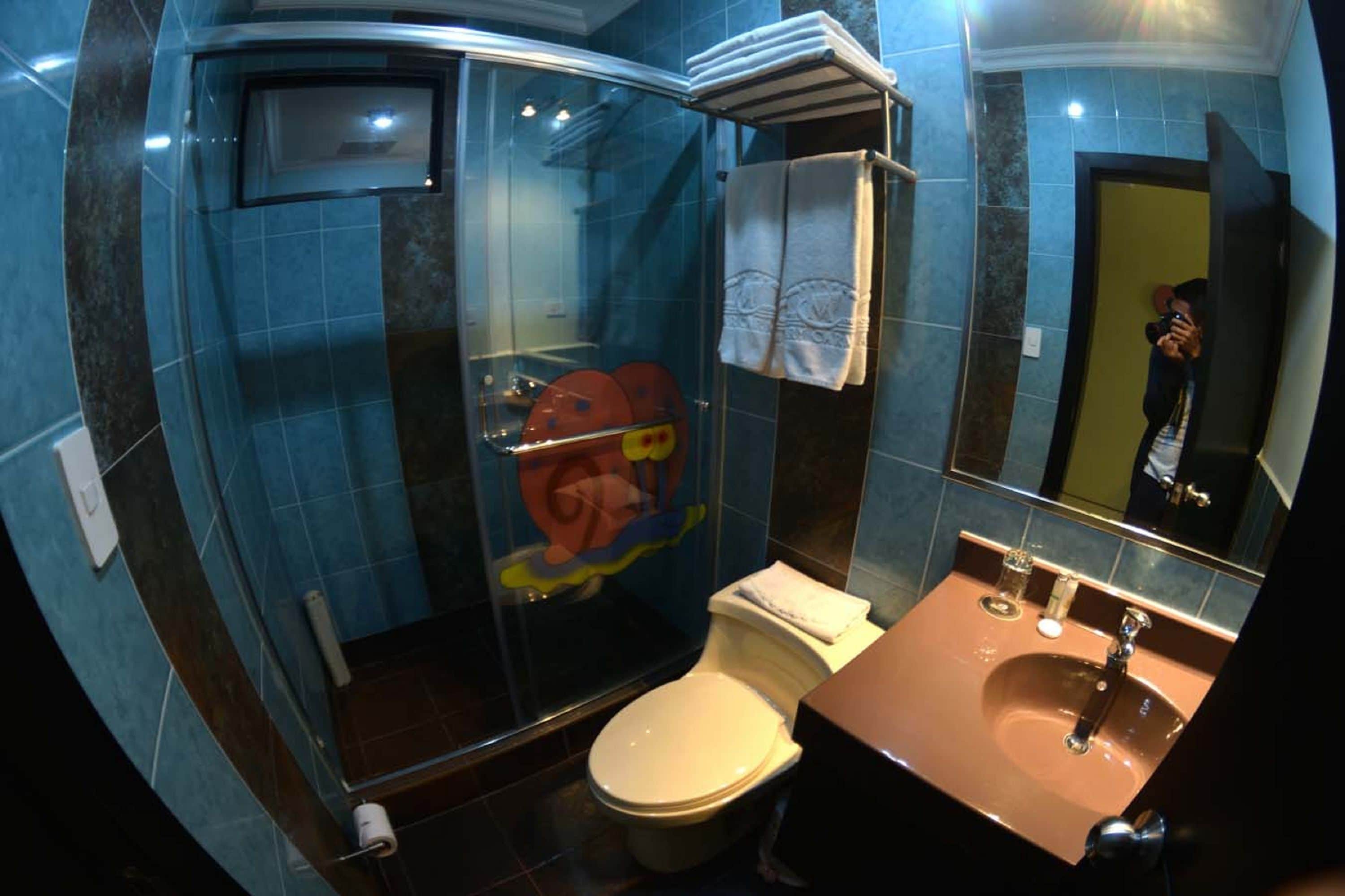 A bathroom with a glass-enclosed shower, a toilet, and a sink with a mirror.