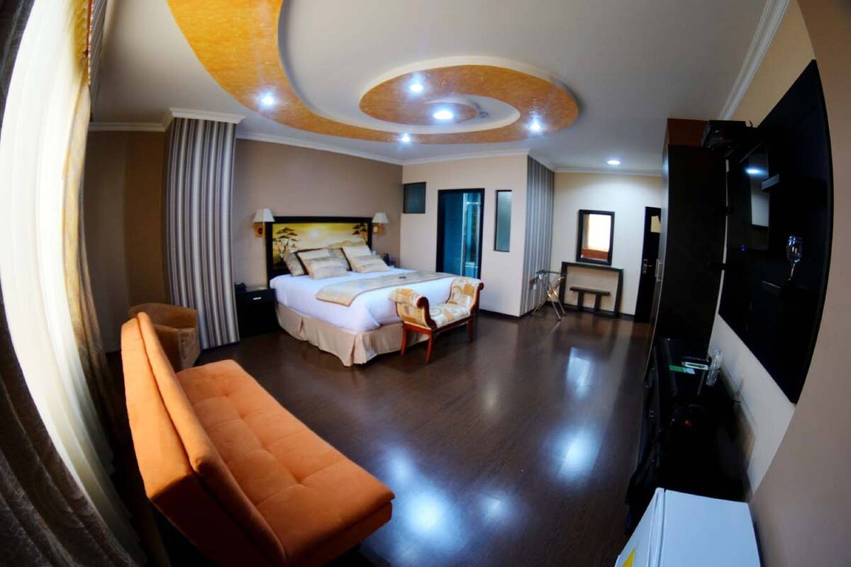 A hotel room with a bed, a sofa, a TV, and a desk.