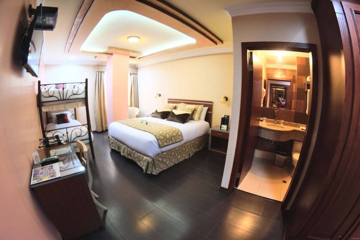A hotel room with a bed, bedside table, and a bathroom visible through an open door.