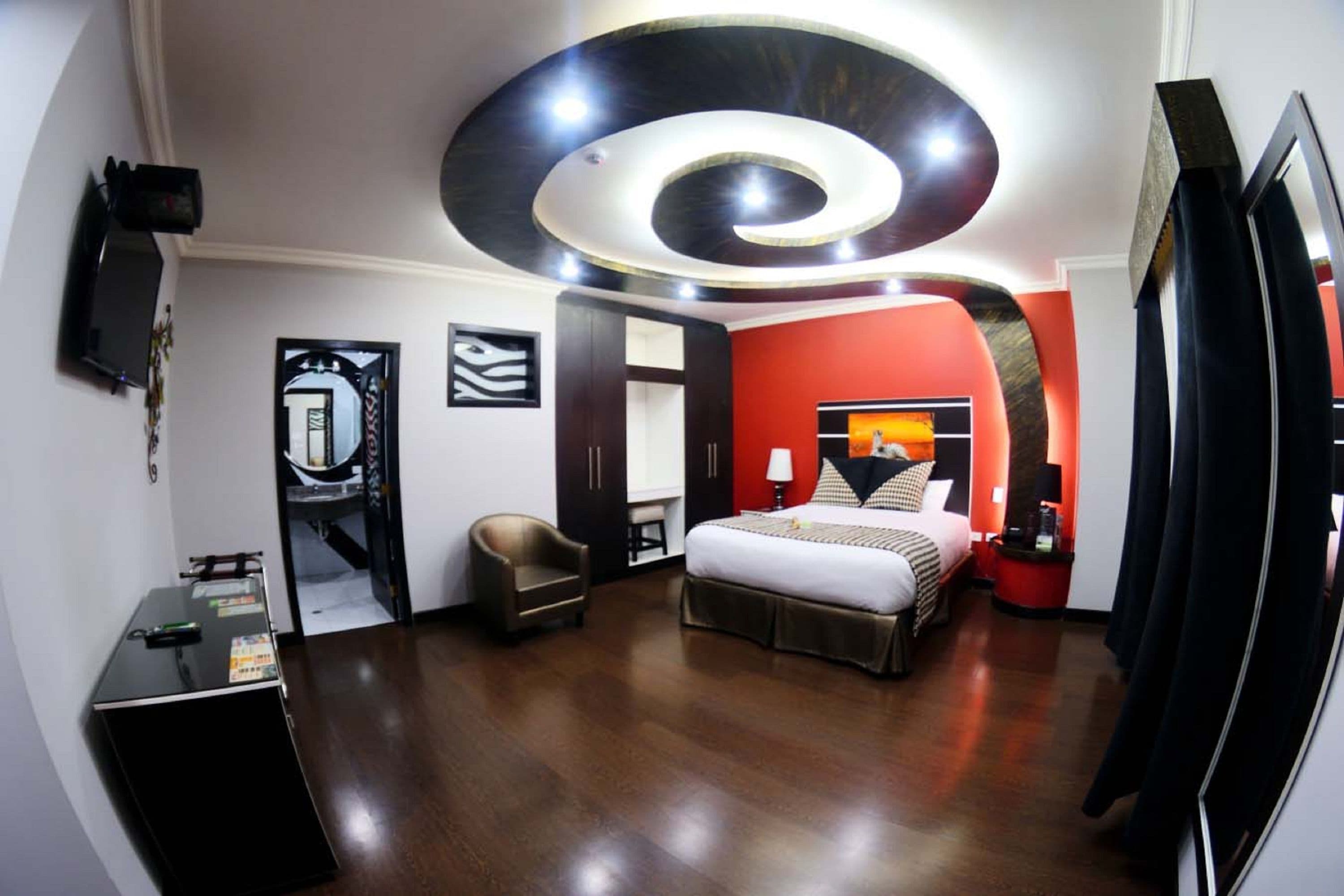 A hotel room with a bed, a desk, a chair, and a TV.