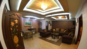 A spacious living room with a dining area, featuring a chandelier, sofas, and a decorative door. - Hotel Boutique Mary Carmen (Ambato)
